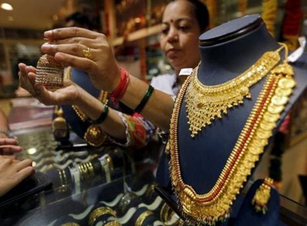 A salesperson shows a gold earring to customers at a jewellery showroom in Mumbai in this file photo. (Reuters Photo) A salesperson shows a gold earring to customers at a jewellery showroom in Mumbai in this file photo. (Reuters Photo)
