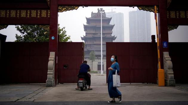 A woman wearing a protective face mask walks past a temple in Wuhan. The decision to carry out large-scale testing was made as the city continued to report asymptomatic infections daily. (Aly Song / REUTERS)