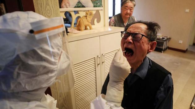 A medical worker takes a swab sample from an elderly resident who is unable to leave home to participate in the COVID-19 testing. Each district of the city will now get 10 days to complete the tests. (STR / AFP / China OUT )