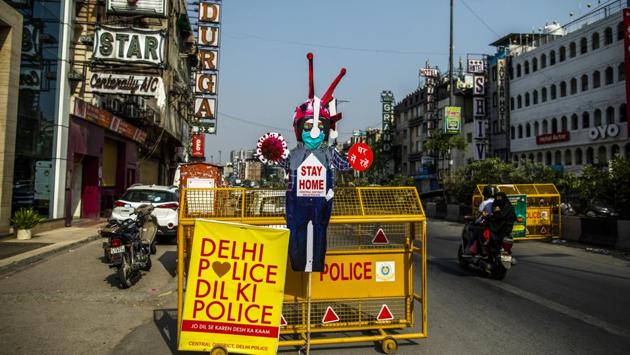 Motorcyclists drive past an effigy reading "Stay Home" at a police barricade in New Delhi. The central government has announced ₹15,000 crore healthcare funds to fight Covid-19. (Prashanth Vishwanathan / Bloomberg)