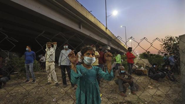 A girl of a migrant worker looks at the policemen stopping other migrant worker to cross Delhi, Uttar Pardesh border to reach their villages during lockdown to prevent the spread of new coronavirus in New Delhi. (AP) A girl of a migrant worker looks at the policemen stopping other migrant worker to cross Delhi, Uttar Pardesh border to reach their villages during lockdown to prevent the spread of new coronavirus in New Delhi. (AP)