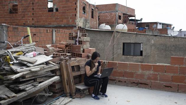 Maria Figueroa, a 34-year-old mother of four, seen on the roof of her apartment as she fails to connect to the internet to send pictures of her sons’ homework back to their teachers. It is an uphill task to teach children online in technology-challenged Venezuela, where flipping on the light switch can be a luxury and a strong internet connection, a dream. (Ariana Cubillos / AP) Maria Figueroa, a 34-year-old mother of four, seen on the roof of her apartment as she fails to connect to the internet to send pictures of her sons’ homework back to their teachers. It is an uphill task to teach children online in technology-challenged Venezuela, where flipping on the light switch can be a luxury and a strong internet connection, a dream. (Ariana Cubillos / AP)