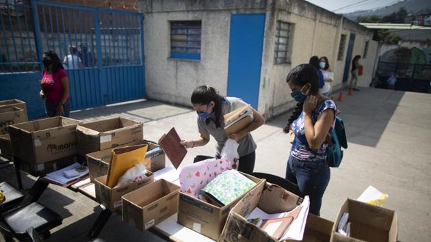 A teacher checks a student list and holds homework brought by parents who do not have access to internet connection at home. (Ariana Cubillos / AP) A teacher checks a student list and holds homework brought by parents who do not have access to internet connection at home. (Ariana Cubillos / AP)