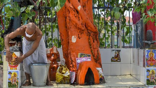 A priest wearing a facemask cleans a temple in New Delhi. All places of worship will remain closed to the public and religious congregations are strictly prohibited during this period. (Kamal Kishore / PTI) A priest wearing a facemask cleans a temple in New Delhi. All places of worship will remain closed to the public and religious congregations are strictly prohibited during this period. (Kamal Kishore / PTI)