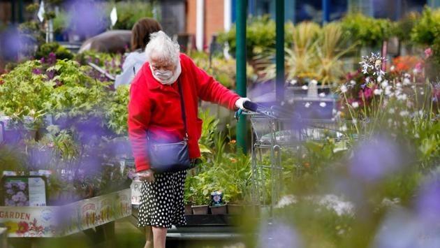 A customer wearing a protective face mask looks at plants for sale at the Grosvenor Garden Centre, operated by Blue Diamond Ltd., in Belgrave, UK on May 15. With the numbers of deaths and infections falling, Prime Minister Boris Johnson is attempting to find a balance between reopening the economy and avoiding a new spike in cases. (Paul Thomas / Bloomberg)