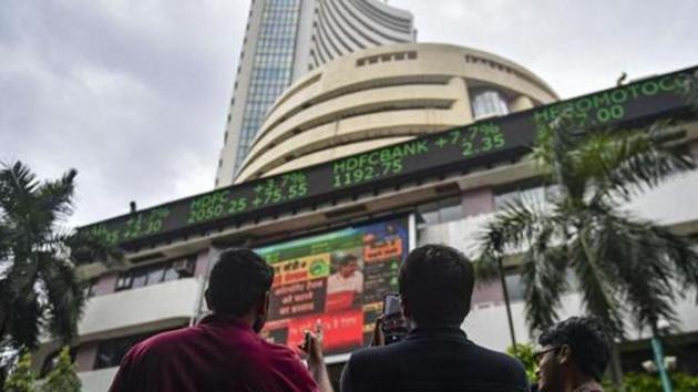 Bystanders react as they watch the stock prices displayed on a digital screen outside BSE building, in Mumbai(PTI)