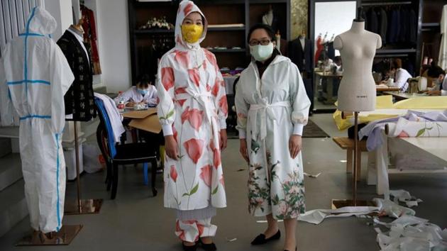 Designer Zhou Li and Ni Zan'er in protective suits and silk face masks designed by Zhou, pose for pictures at a studio in Beijing, following the novel coronavirus disease (COVID-19) outbreak, China May 17, 2020. Picture taken May 17, 2020. REUTERS/Tingshu Wang(REUTERS)