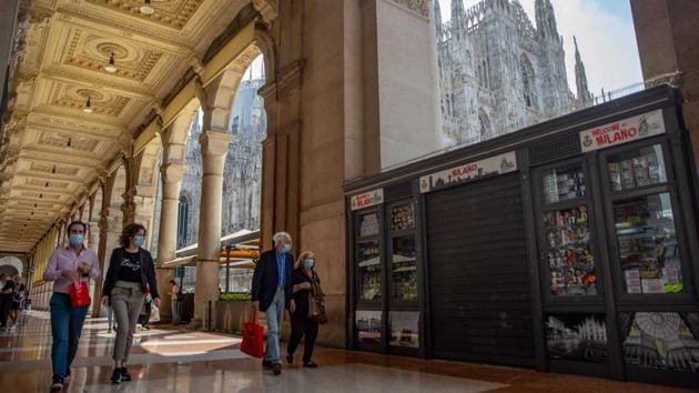 Pedestrians pass a closed tourist souvenir stall in view of the Duomo cathedral in Milan on May 18. Italian shoppers may have begun digging out their wallets as retail businesses reopen but foreign tourists, vital for the economy, remain absent. (Francesca Volpi / Bloomberg)