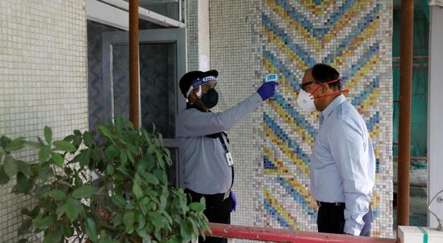 A private security guard uses an infrared thermometer to measure the temperature of an employee joining the office after few restrictions were lifted by Delhi government. (Reuters file photo) A private security guard uses an infrared thermometer to measure the temperature of an employee joining the office after few restrictions were lifted by Delhi government. (Reuters file photo)