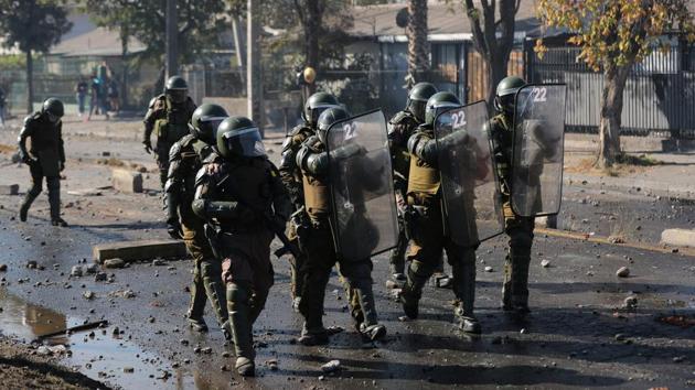 Riot police hold shields along a street littered with stones during the clashes. Chile has already announced a massive stimulus package worth nearly 7% of gross domestic product to ease the economic impact of the pandemic, although opposition leaders and social groups have criticised the package as inadequate. (Ivan Alvarado / REUTERS)