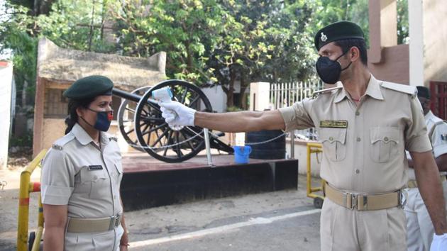 A police personnel undergoes thermal screening at the entry gate of Bihar Military Police (BMP) campus, after it was designated as a containment zone in Bihar on May 17. The number of active cases in the state stands at 916. (Santosh Kumar / HT Photo) 