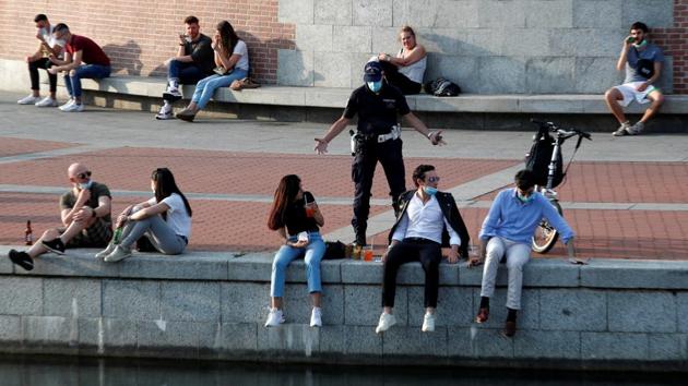 A police officer asks people drinking next to a canal to maintain social distancing in Milan on May 18. It was only day one, but major Italian cities noted higher traffic as people stepped out to catch up with friends. (Alessandro Garofalo / REUETRS)