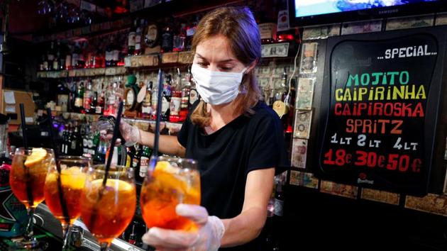A bartender wearing a protective mask and gloves prepares cocktails in Rome’s bohemian Trastevere neighbourhood on May 18. Customers will now once again be able to sip their beverage of choice at bars, albeit well spaced from other clients. Restaurants are able to serve as long as tables are kept at least 2 metres apart. (Guglielmo Mangiapane / REUTERS)