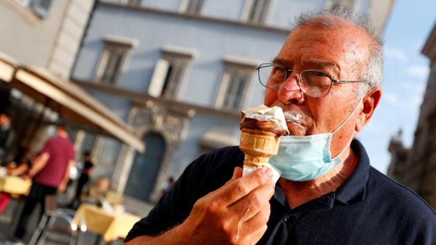 A man wearing a protective mask enjoys an ice-cream in Trastevere on May 18. Italy is scheduled to open up borders with Europe and allow free travel between the regions from June 3. (Guglielmo Mangiapane / REUTERS)