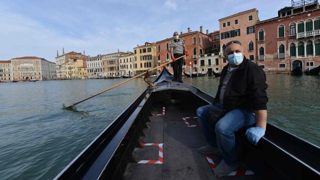 A gondolier wearing a face mask transports his very first customer as service resumes at the San Toma embankment on a Venice canal on May 18 during Italy’s eased exit from a lockdown aimed at curbing the spread of the COVID-19 infection that began 10 weeks ago on March 9. (Andrea Pattaro / AFP)