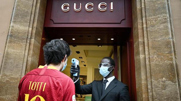 A fan of AS Roma wearing a Francesco Totti jersey undergoes a temperature check as he enters a Gucci store in Via dei Condotti in central Rome on May 18. Concerns linger among business owners that the reopening may not magic away their many problems as fears linger of the coronavirus keeping many Italians at home. (Alberto Pizzoli / AFP)