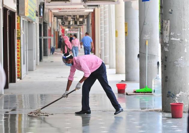 A man cleaning the corridor before opening a shop at the Plaza in Sector 17 in Chandigarh on Tuesday.(Ravi Kumar/HT)