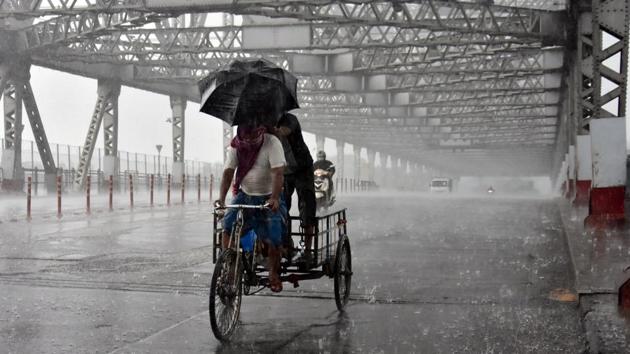 A cycle rickshaw crosses the iconic Howrah Bridge in Kolkata in the middle of a heavy downpour. The landfall process has triggered intense rain and gusty winds and will continue for about four hours, according to IMD. (ANI)