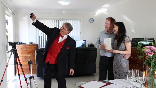 Celebrant Lou Szymkow takes a selfie with groom Peter Andrews and bride Hoang Nguyen after officiating a small wedding ceremony at their home, with loved ones unable to attend due to the coronavirus disease (COVID-19) travel restrictions watching over live stream, in Sydney, Australia, May 19, 2020. REUTERS/Loren Elliott (REUTERS)