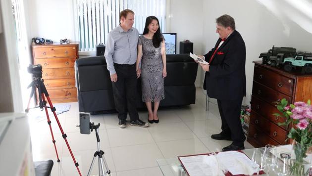 Groom Peter Andrews and bride Hoang Nguyen get married in a small wedding ceremony at home as celebrant Lou Szymkow officiates, with loved ones unable to attend due to the coronavirus disease (COVID-19) travel restrictions watching over live stream, in Sydney, Australia, May 19, 2020. REUTERS/Loren Elliott (REUTERS)