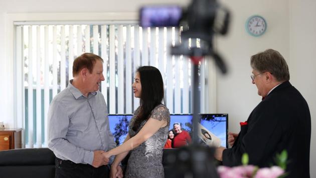 Groom Peter Andrews and bride Hoang Nguyen get married in a small wedding ceremony at home as celebrant Lou Szymkow officiates, with loved ones unable to attend due to the coronavirus disease (COVID-19) travel restrictions watching over live stream, in Sydney, Australia, May 19, 2020. REUTERS/Loren Elliott (REUTERS)