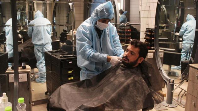 Hairdressers at work in a salon while clad in personal protective equipment (PPE) coveralls in Gurugram.  (Yogendra Kumar / HT Photo) 