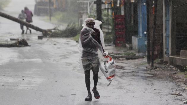 A man covers himself with a plastic sheet and walks in the rain at Bhadrak district, Odisha, on May 20. Heavy rainfall and strong winds are lashing Chandipur in Balasore district and Jagatsinghpur in Odisha as Amphan made landfall in West Bengal. (AP)