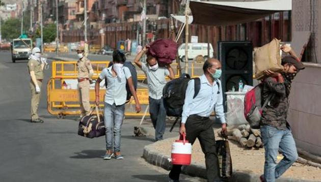 People carrying luggage pass barricades placed at the Ramganj coronavirus hotspot in Jaipur, Rajasthan, India on Monday, May 18, 2020.(Himanshu Vyas/ Hindustan Times)