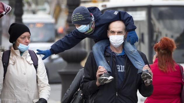 A family wearing face masks to protect against coronavirus walk in St.Petersburg on May 19. Moscow remains Russia’s worst hit region and is now in its eighth week of a lockdown. Citizens remain largely confined to their homes unless they obtain digital passes to make certain journeys. (Dmitri Lovetsky / AP)