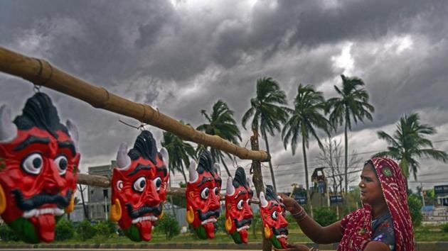 A woman dries clay demon masks on a roadside as dark clouds gather over the city ahead of landfall by Cyclone Amphan on the outskirt of Bhubaneswar, Odisha. (PTI) A woman dries clay demon masks on a roadside as dark clouds gather over the city ahead of landfall by Cyclone Amphan on the outskirt of Bhubaneswar, Odisha. (PTI)