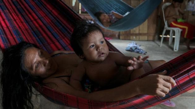 Priscila Tavares Batista, 36 lies in a hammock with her son Jone Tavares, 2, after being treated with medicinal herbs for symptoms of COVID-19, in the Wakiru community. The virus has infected 40 indigenous groups with 537 positive cases and 102 deaths according to the Brazilian Indigenous Peoples’ Association, AFP reported on May 19. (Ricardo Oliveira / AFP)