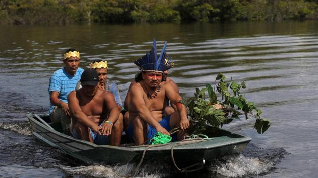 Satere-Mawe indigenous leader Andre Satere (R) and others on an expedition to collect medicinal plants. In this small motor boat, five men from the Satere Mawe tribe are trying to help their people survive without using the saturated state health system in Amazonas, which despite its remoteness is one of the places hit hardest by the pandemic in Brazil. (Ricardo Oliveira / AFP)