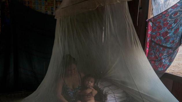 Priscila Tavares Batista in a bed covered by a mosquito net with her son after being treated with medicinal herbs. Andre Satere’s group and others have moved closer to state capital Manaus in recent decades, but aren’t relying on the city’s health services. “They’ve been forced to choose who gets care and who doesn’t -- and we don’t,” he said. (Ricardo Oliveira / AFP)