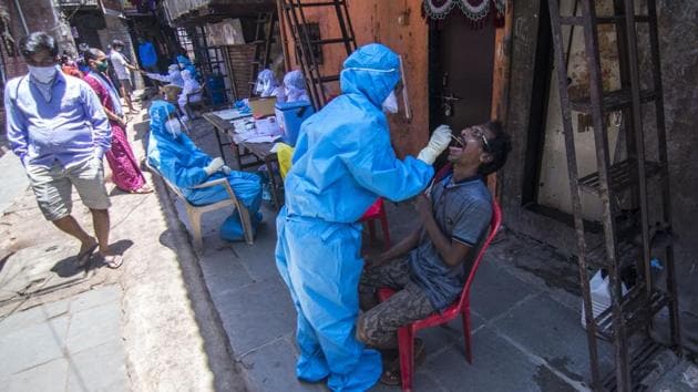 A doctor takes a swab sample of a resident at a coronavirus testing drive inside the Dharavi slums.(Pratik Chorge/HT Photo)