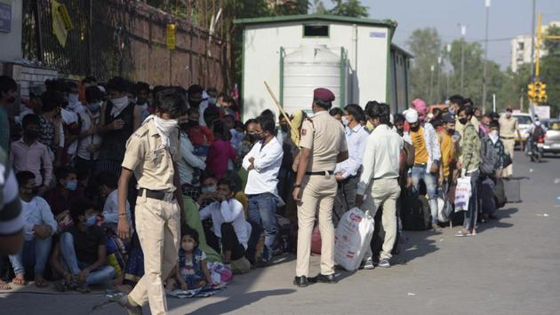 A Delhi Police personnel raises his baton to ensure order among stranded migrant workers gathered at the school. Although all of them reached there after receiving a text message confirming their reservations, many were turned back by officials who said trains were full and their names were not on the list, reported HT on May 21. (Sushil Kumar / HT Photo)