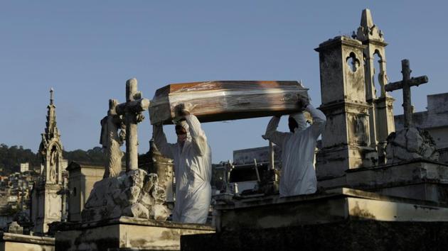 Gravediggers carry a coffin of a person who passed away from the coronavirus disease, in Rio de Janeiro, Brazil. (REUTERS)