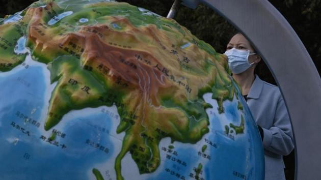 A woman wearing a mask against the coronavirus looks at a globe showing China, in Wuhan in central China's Hubei province.(AP photo)