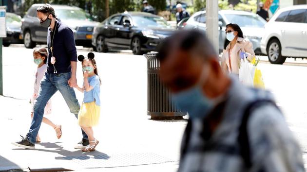 A man holds the hands of two young girls wearing masks as they cross the street as residents of New York City adjust to living with the ongoing outbreak of the coronavirus disease in the Manhattan borough of New York on Wednesday. (Reuters Photo) A man holds the hands of two young girls wearing masks as they cross the street as residents of New York City adjust to living with the ongoing outbreak of the coronavirus disease in the Manhattan borough of New York on Wednesday. (Reuters Photo)