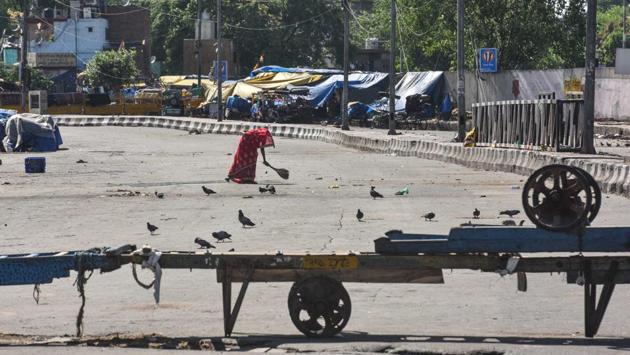 Hand pushcarts form a barricade as a woman sweeps the road leading to Mithai Pul in Sadar Bazar. The traders of the market are fearful of Covid-19 because a majority of them are in their late 50s and 60s, running the business with the help of their employees, their children having refused to join, with the poor working conditions in the market. (Sanchit Khanna / HT Photo)
