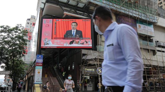 Pedestrians wearing protective masks walk past a screen playing a news report on Chinese Premier Li Keqiang speaking at the National People's Congress in Hong Kong, China. (Bloomberg) Pedestrians wearing protective masks walk past a screen playing a news report on Chinese Premier Li Keqiang speaking at the National People's Congress in Hong Kong, China. (Bloomberg)