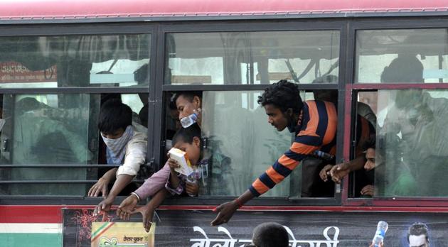 Migrants in a bus reaching out for water being distributed by local residents, at Bhitholi Chauraha, Lucknow, Uttar Pradesh, India on Wednesday, May 20, 2020.(Photo by Dheeraj Dhawan / Hindustan Times)