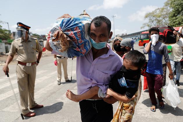 A migrant carries luggage and his child as he arrives at a railway station to board a train to their home state of Uttar Pradesh during an extended lockdown to slow the spread of the coronavirus disease (Covid-19), in Mumbai, India.(REUTERS)
