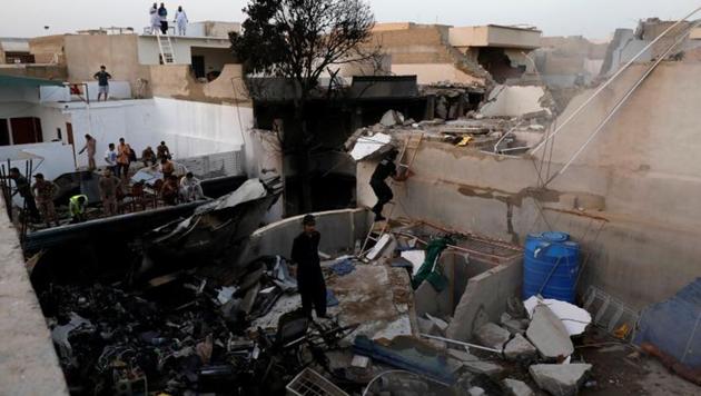 People stand on a roof of a house amidst debris of a passenger plane, crashed in a residential area near an airport in Karachi, Pakistan on May 22, 2020.(Reuters Photo)