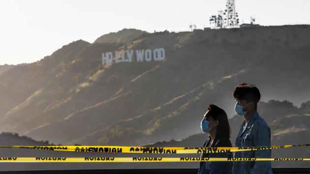 People wearing face masks at he Griffith Observatory with a view of the Hollywood sign at the start of Memorial Day holiday weekend. Social distancing and bans on mass gatherings remain in place throughout much of the country. People are advised to stay away from places with large crowds. (Apu Gomes / AFP)