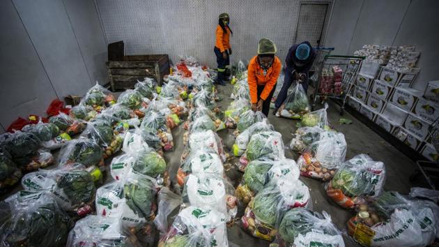 Volunteers from a food bank sort bags containing food aid for distribution at Springs Fresh Produce Market, east of Johannesburg, South Africa, on Thursday. (Bloomberg) Volunteers from a food bank sort bags containing food aid for distribution at Springs Fresh Produce Market, east of Johannesburg, South Africa, on Thursday. (Bloomberg)