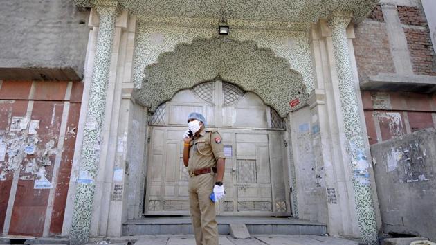 A police personnel on guard during a visit by Commissioner of police Alok Singh at the Sector 8 Jama Masjid ahead of Eid to check the law and order situation and to speak with locals about social distancing and safety, in Noida. (Sunil Ghosh / Hindustan Times)