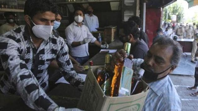 A man buys bottles of liquor outside a wine store during a nationwide lockdown to curb the spread of new coronavirus in Jammu.(AP File Photo)