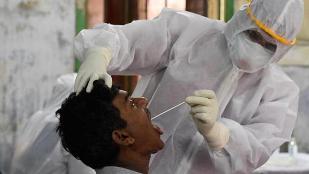 A medical professional wearing PPE suit takes a swab sample from a man for Covid-19 test during lockdown.(Samir Jana / Hindustan Times)