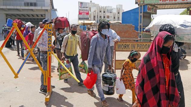 Migrant workers and their families stand in a queue waiting for buses to move towards the railway station to board a train to their home state, in Ahmedabad on Friday. (ANI Photo)