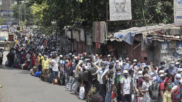 Migrant workers and their family members stand in a queue and wait for the bus at Dharavi to go to the Lokmanya tilak terminus as a special train organised by Maharashtra government to go their native place, on Sunday.(Satyabrata Tripathy/HT Photo)